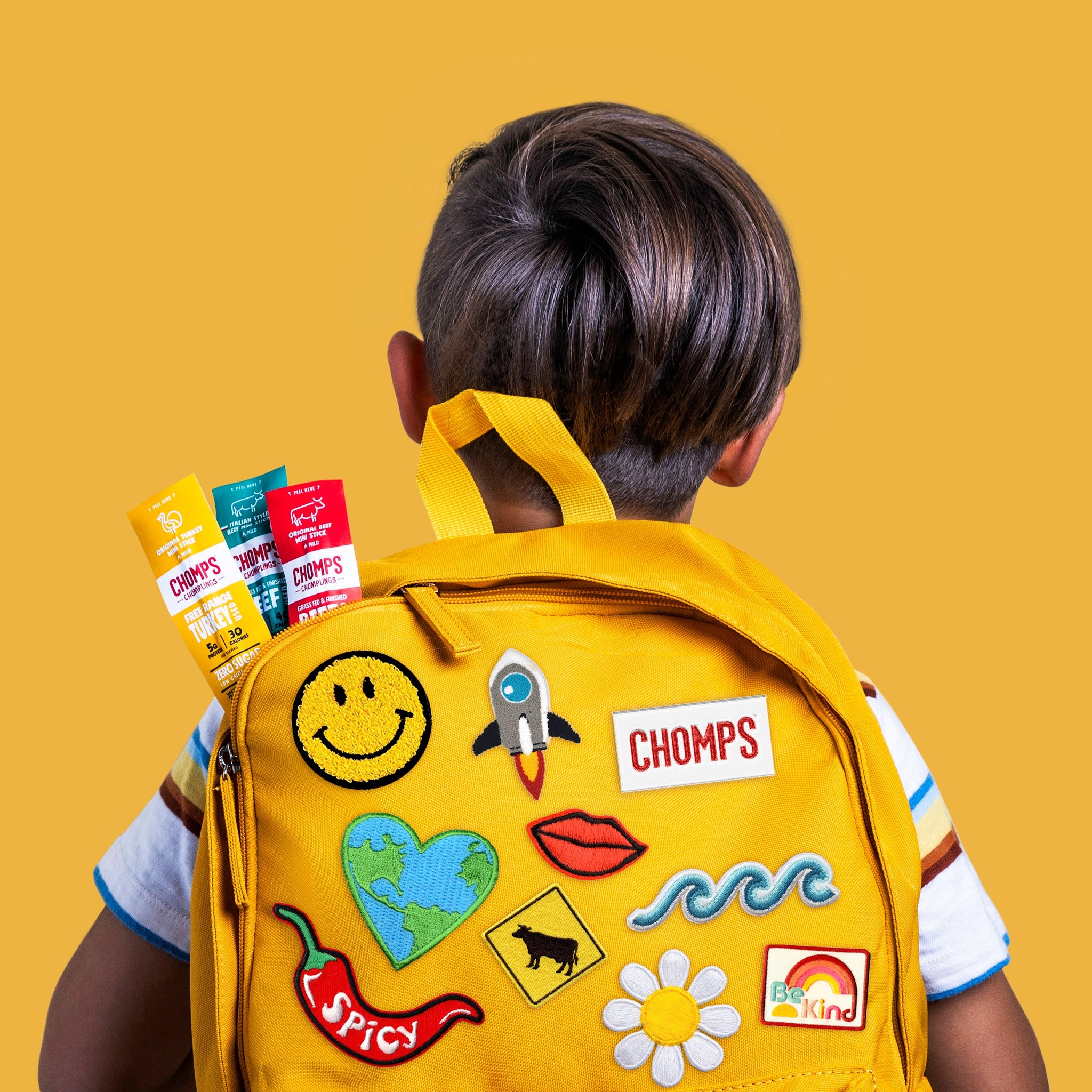 A young boy with a yellow backpack full of Chomps
